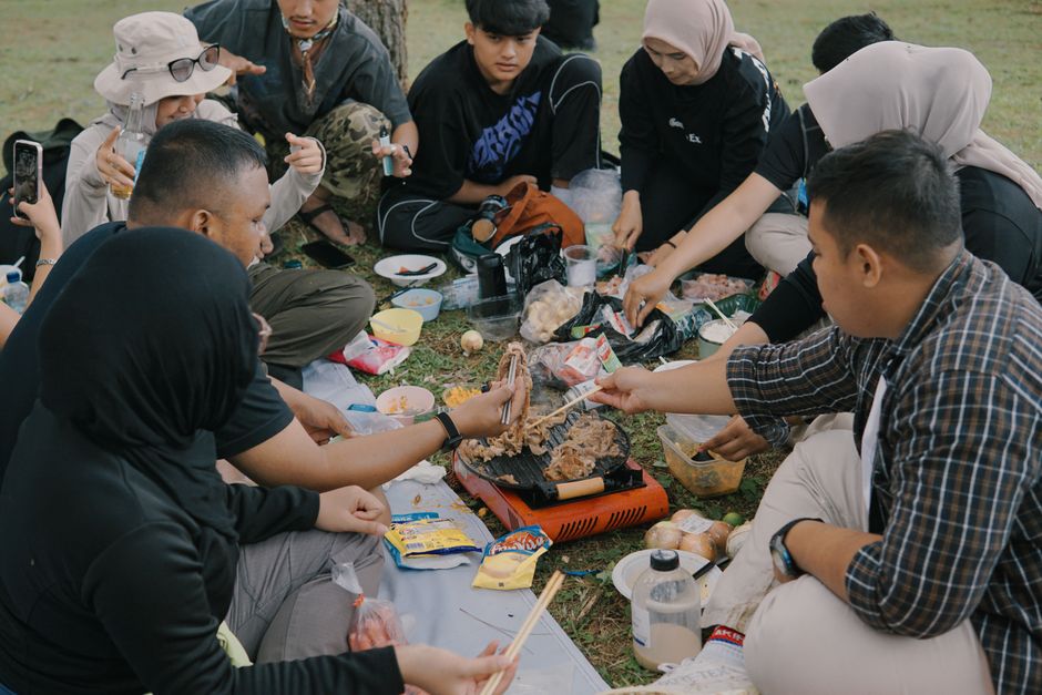 A group of friends enjoying a picnic and barbecue outdoors in Jawa Barat, Indonesia.
