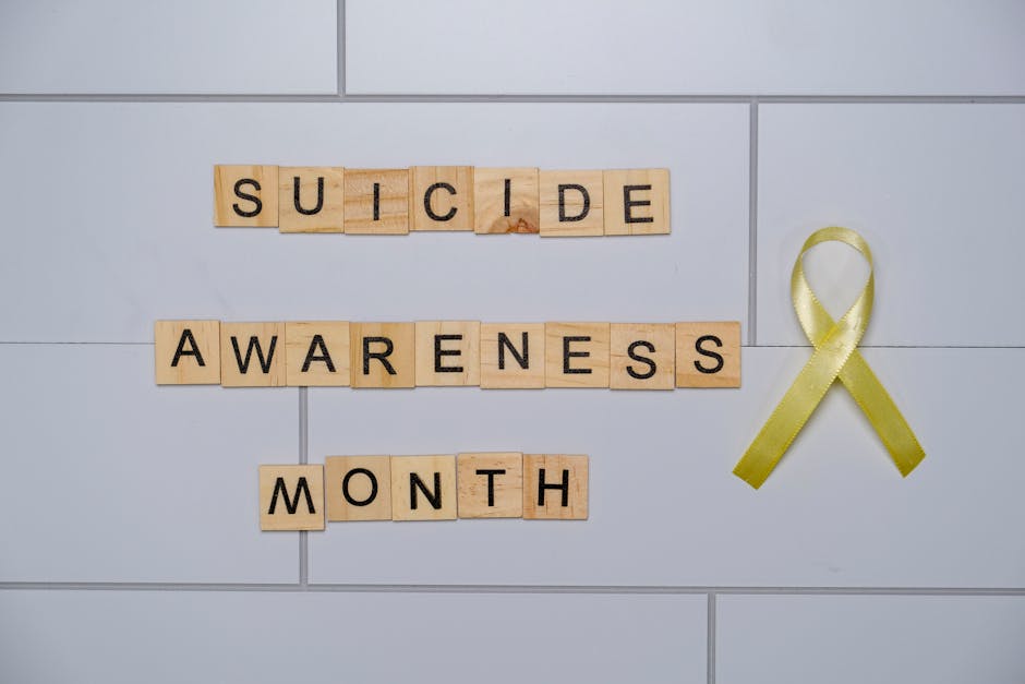 Wooden blocks spelling 'Suicide Awareness Month' with a yellow ribbon.